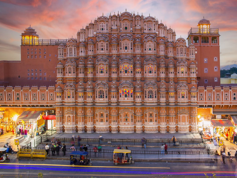 Stunning view of the Hawa Mahal at sunset with blurred people walking in Jaipur.